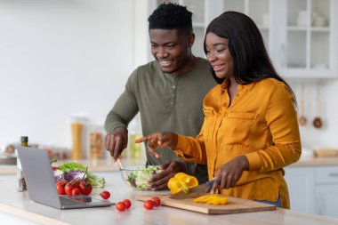 Neşeli Siyah Eşler Mutfakta Yemek Pişiriyor ve Laptoptaki Tarifleri Kontrol Ediyor