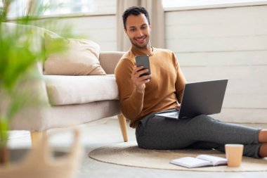 Evde akıllı telefon ve bilgisayar kullanan bir adamın portresi