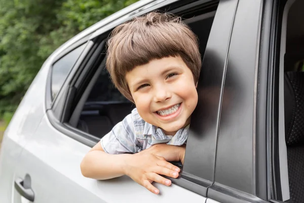 Feliz niño pequeño mira por la ventana abierta y disfruta de viaje con sus padres en coche, al aire libre en verano, espacio para copiar —  Fotos de Stock