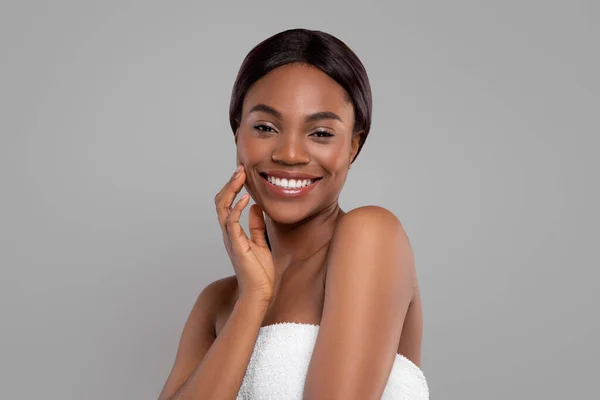 Happy pretty black female enjoying perfect soft skin after spa procedures, isolated on gray background, copy space — Stock Photo, Image