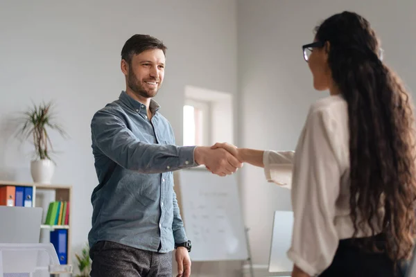 Happy businessman shaking hands with young businesswoman at office. HR manager welcoming job applicant into company team — Stock Photo, Image