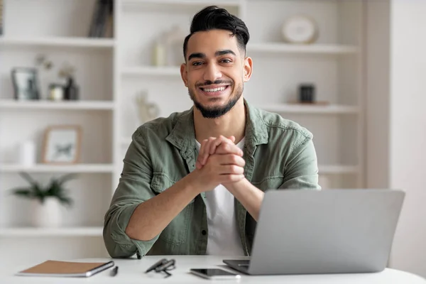 Encantado joven islámico guapo con barba en el lugar de trabajo con el ordenador portátil en el interior de la oficina en casa — Foto de Stock