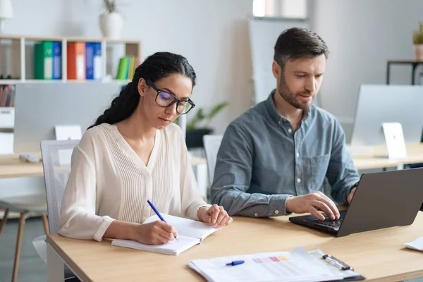 Fröhliche Kollegen, die gemeinsam am Startup-Projekt arbeiten, am Laptop arbeiten, im modernen Büro Informationen aufschreiben — Stockfoto