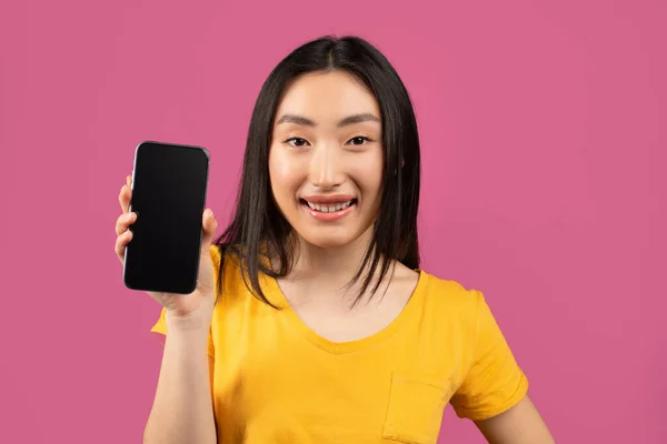 Mockup pro aplikaci nebo webové stránky. Asijské dáma ukazuje smartphone s prázdnou obrazovkou přes fialové studio pozadí — Stock fotografie