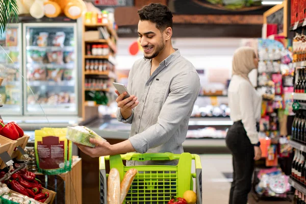 Arabic Male Using Smartphone During Shopping Scanning Vegetables In Supermarket — ストック写真