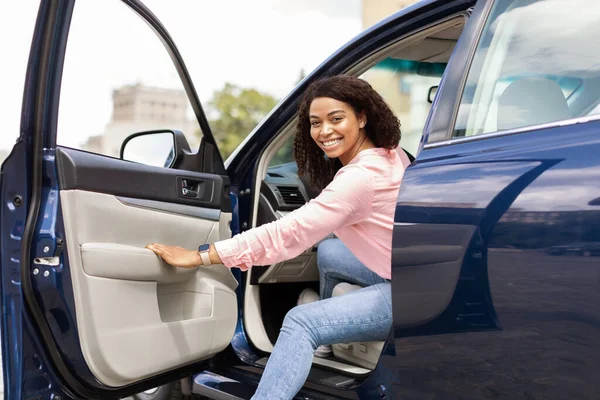 Smiling black woman driving new car in the city