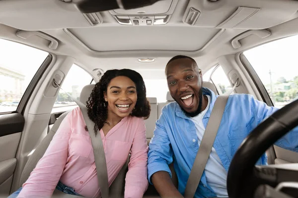 Feliz pareja negra sentada en el coche mirando la cámara — Foto de Stock