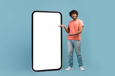 Doğulu şık adam büyük cep telefonunun yanında duruyor.