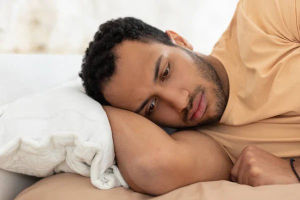 Арабский парень с депрессией и бессонницей лежит в постели в помещении — стоковое фото