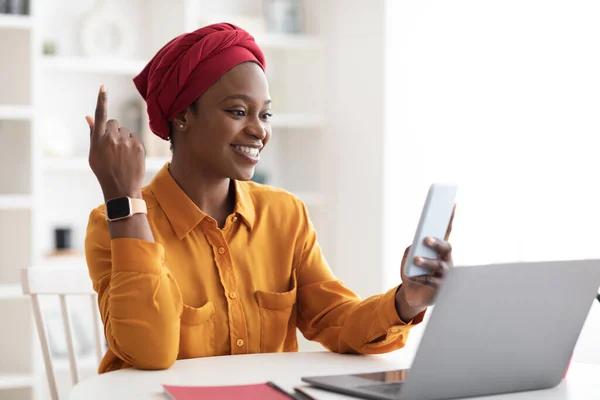 Empresária afro-americana positiva usando smartphone e laptop — Fotografia de Stock
