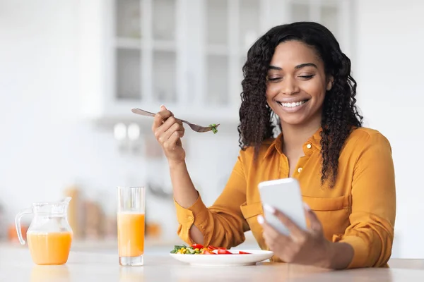 Felice donna nera che naviga sui social media mentre fa colazione — Foto Stock