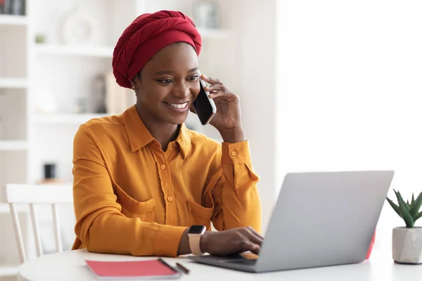 Donna nera musulmana positiva che lavora su computer portatile a ufficio — Foto Stock
