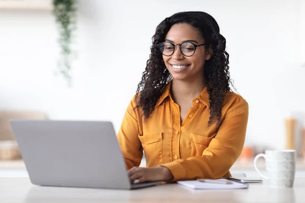 Positieve Afrikaanse Amerikaanse vrouw freelancer met behulp van laptop thuis — Stockfoto