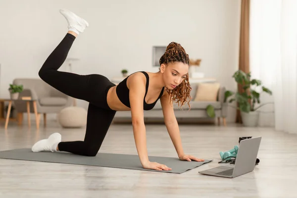 Spor Afrikalı Kadın Dizüstü bilgisayarın yanında dört ayak üstünde egzersiz yapıyor. — Stok fotoğraf