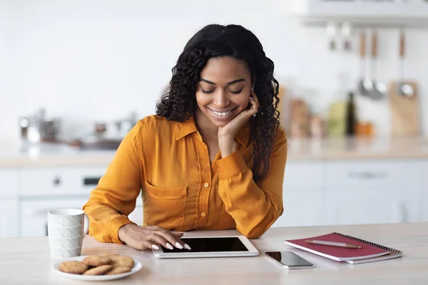 Glimlachende zwarte dame freelancer werken vanuit huis, met behulp van digitale tablet — Stockfoto