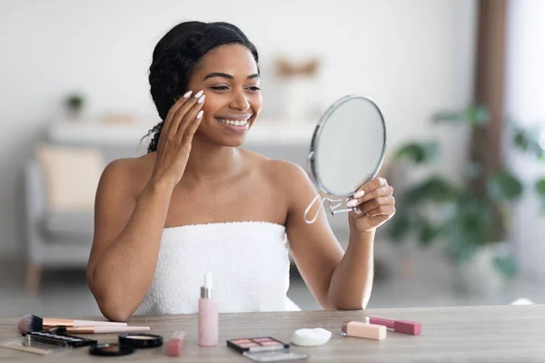 Mooie jonge zwarte vrouw van toepassing make-up en glimlachen — Stockfoto