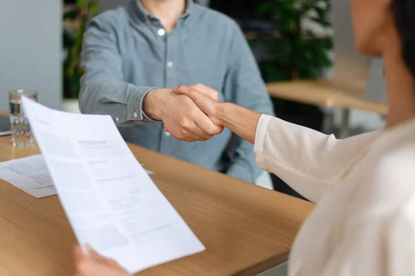 Unrecognizable HR manager shaking hands with successful vacancy candidate after work interview at modern office