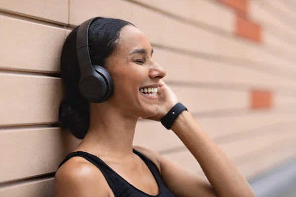 Feliz milenar atleta mulher do Oriente Médio com fones de ouvido gosta de música favorita no fundo da parede de tijolo — Fotografia de Stock
