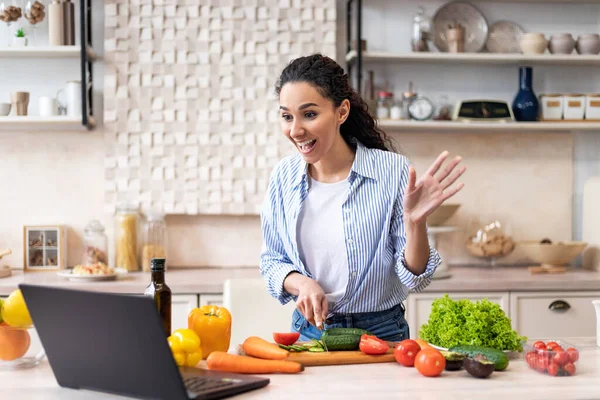 Bereiten Sie das Essen zu Hause zu. Aufgeregte Dame bereitet Salat zu und unterhält sich in der Küche per Laptop im Videochat — Stockfoto