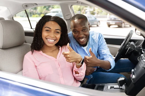 Счастливая чёрная пара, сидящая в машине и показывающая пальцами вверх — стоковое фото