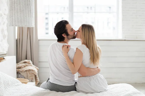 Junge liebevolle kaukasische Paar umarmen und küssen sich auf dem Bett zu Hause, Kopierraum — Stockfoto