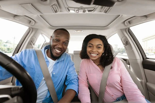Счастливая чёрная пара, сидящая в машине, позируя перед камерой — стоковое фото