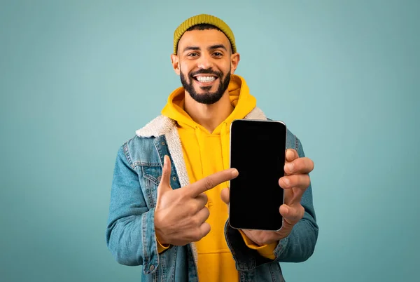 Stijlvolle Arabisch man wijzend naar smartphone met zwart scherm — Stockfoto