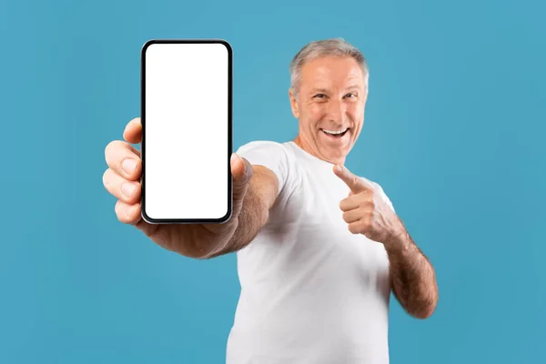 Захоплений зрілий чоловік вказує пальцем на порожній екран смартфона — стокове фото