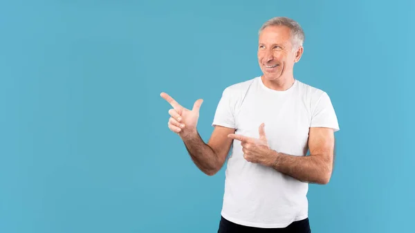 Excited mature man pointing aside at copy space — Stockfoto