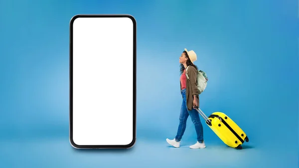 Negro señora turista mirando el teléfono caminando sobre fondo azul — Foto de Stock