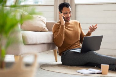 Arap adam evde çalışıyor ve telefonla konuşuyor.