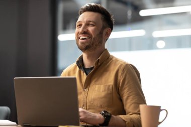 Başarılı İşadamı Laptop kullanıyor ve işyerinde yan yan bakıp gülüyor