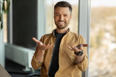 İş adamı kameraya gülümsüyor. Ofiste otururken görüntülü arama yaptırıyor.