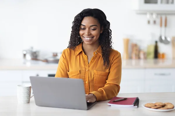 Heureuse femme noire qui travaille à la maison, dactylographiant sur ordinateur portable — Photo