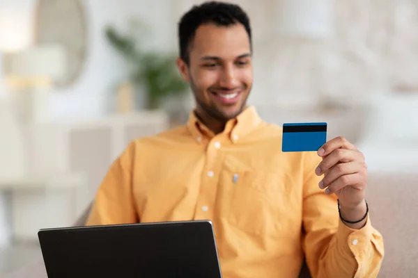 Hombre sonriente usando PC y tarjeta de crédito en casa —  Fotos de Stock