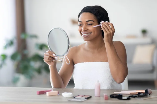 Aantrekkelijke zwarte vrouw aanbrengen concealer na douche — Stockfoto