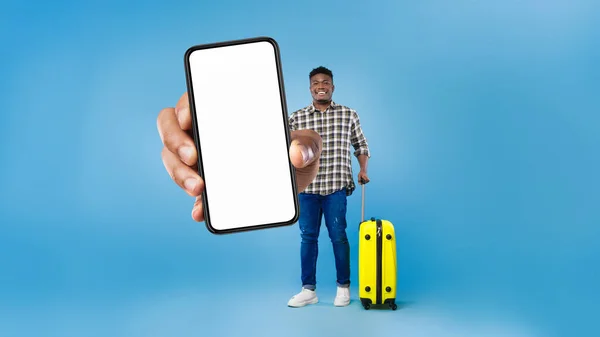 Turista masculino negro sosteniendo Smartphone mostrando pantalla sobre fondo azul — Foto de Stock