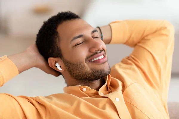 Homem árabe calmo tendo descanso em casa ouvindo música — Fotografia de Stock