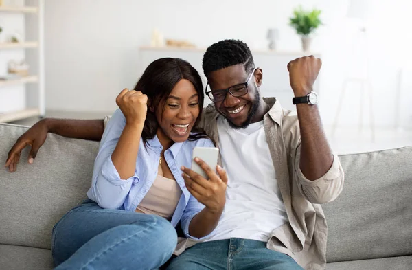 Afrikaans Amerikaans paar met behulp van mobiele telefoon, vieren overwinning — Stockfoto