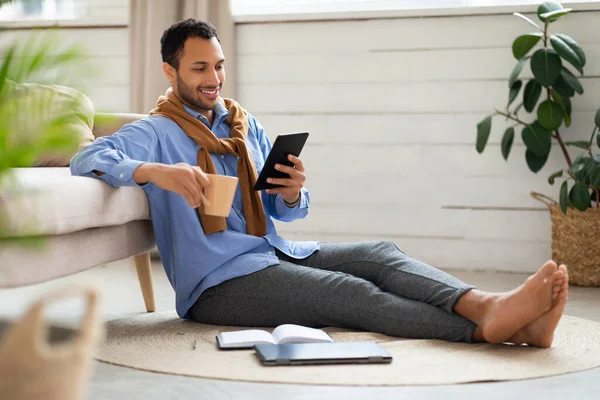 Evde tablet kullanan gülümseyen genç adamın portresi