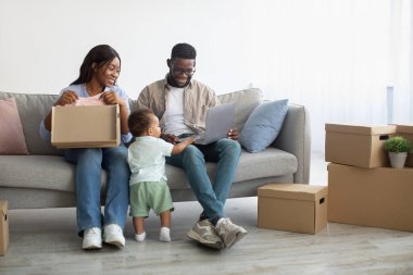 Mutlu siyah erkek kadın ve çocuk taşındıktan sonra bilgisayar kullanıyor.