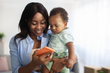 Evde cep telefonu kullanan Afrikalı Amerikalı annenin portresi.
