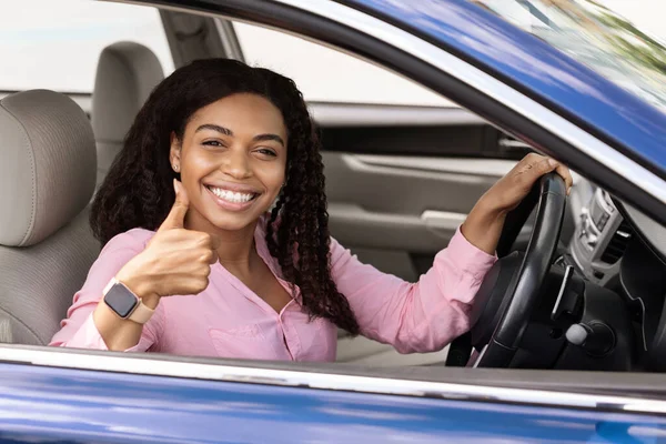 Feliz mujer negra sentada en el coche mostrando como gesto — Foto de Stock