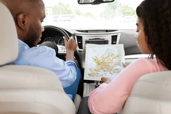 Feliz pareja negra mirando el mapa de papel sentado dentro del coche —  Fotos de Stock