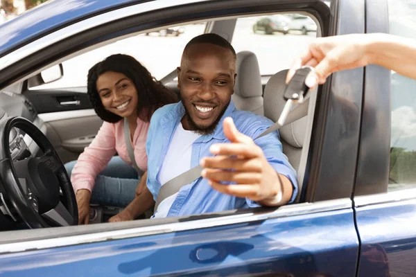 Feliz negro pareja sentado en nuevo coche tomando llaves —  Fotos de Stock