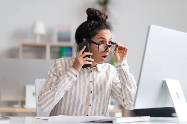 Probleme am Arbeitsplatz. Geschockte Geschäftsfrau telefoniert und schaut auf Computerbildschirm, arbeitet im Büro — Stockfoto