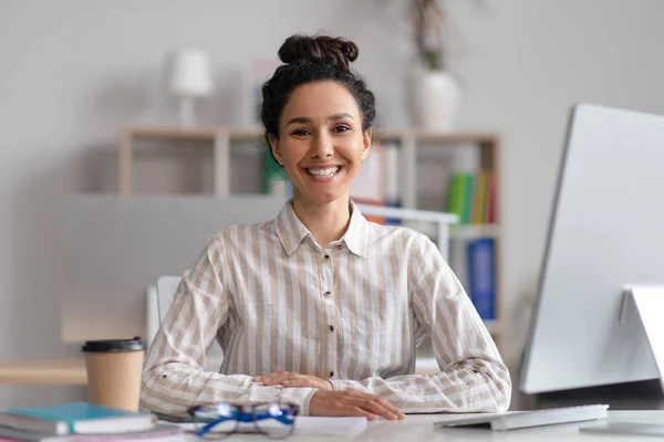 Πορτρέτο της χαρούμενης γυναίκα διευθυντής κάθεται στο χώρο εργασίας στο σύγχρονο γραφείο και χαμογελώντας στην κάμερα — Φωτογραφία Αρχείου