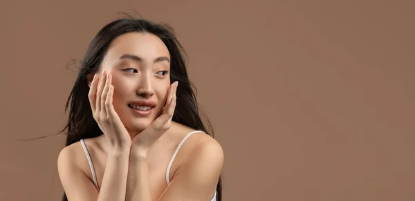 Schoonheidsconcept. Gelukkig jong aziatisch vrouw met vlekkeloze huid en natuurlijke make-up, kijken opzij op vrije ruimte, panorama — Stockfoto