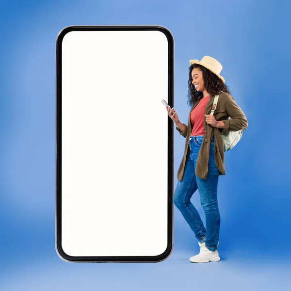 Turista femenina afroamericana usando teléfono móvil sobre fondo azul — Foto de Stock