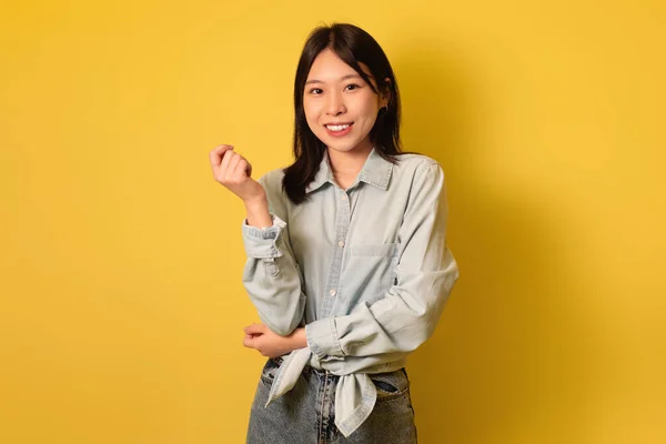 Retratos de pessoas reais. Jovem mulher asiática feliz com cabelo escuro olhando para a câmera e sorrindo sobre o fundo amarelo — Fotografia de Stock